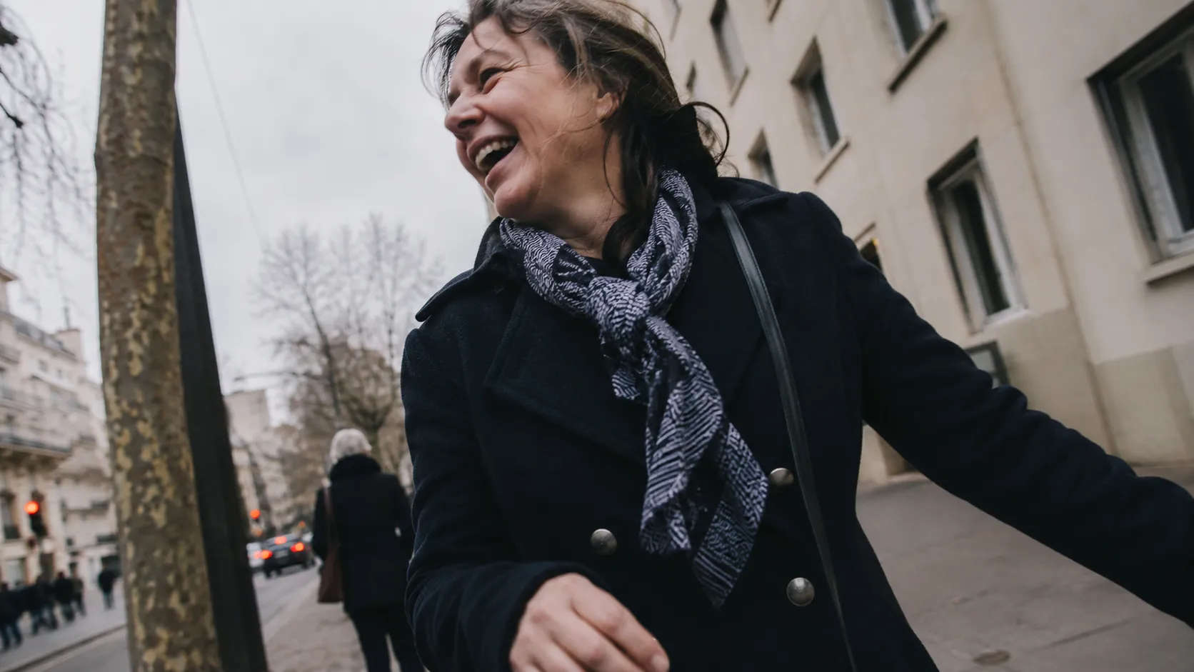 Femme souriante marchant dans une rue ensoleillée après un divorce